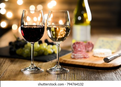two glass of red wine and white wine with french cheese and delicatessen in restaurant wooden table with romantic dim light and cosy atmosphere