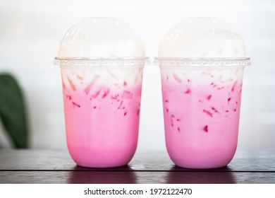 Two glass of Thai style iced pink sweet milk in coffee shop on wood table