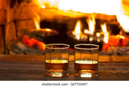 Two glasses of alcoholic drink wine and antique books in front of warm fireplace. Magical relaxed cozy atmosphere near  fire. Background horizontal - Powered by Shutterstock