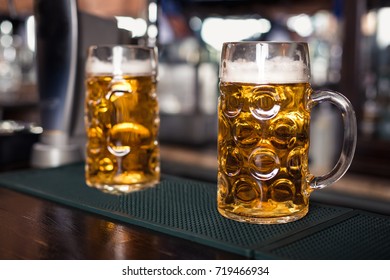 Two glasses of beer on a bar table. Beer tap on background