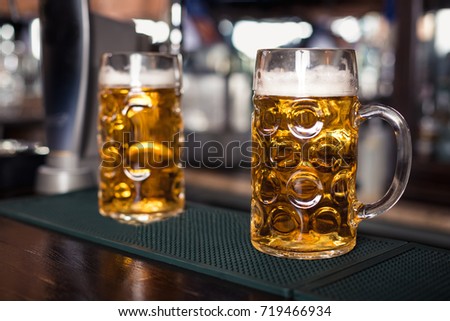 Two glasses of beer on a bar table. Beer tap on background