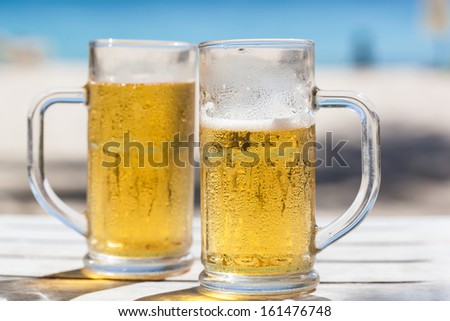 Two glasses of beer on a beach 