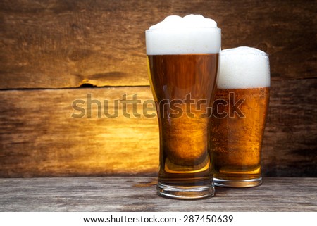 two glasses of beer over vintage wood background