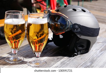 Two glasses of beer and a ski helmet on the table