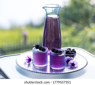 Two Glasses Of Blackberry Mocktail Served On A Metal Tray Garnished With Blackberry Skewers.