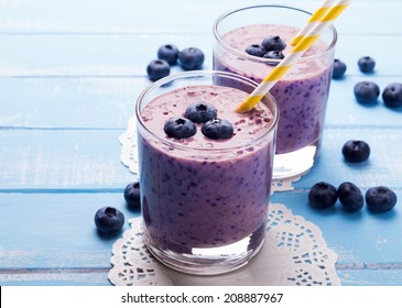 Two glasses of blueberry smoothie on blue colored wooden table - Powered by Shutterstock