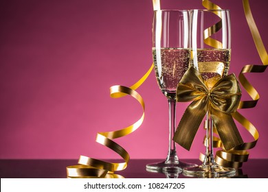 Two Glasses Of Champagne With Bow On Pink Background