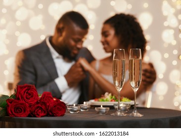 Two glasses of champagne and bunch of red roses over black couple in love, celebrating Valentine's Day at restaurant