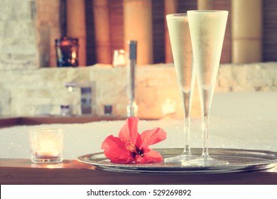 Two glasses of champagne with candle and red flower near jacuzzi. Valentines background. Romance concept. Horizontal, toned