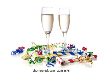 Two Glasses Of Champagne With Party Noise Maker And Streamers On A White Background.  New Year's Eve Theme