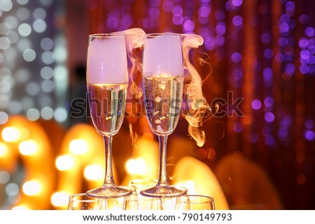 two glasses of champagne with smoke. lightbulbs on the background