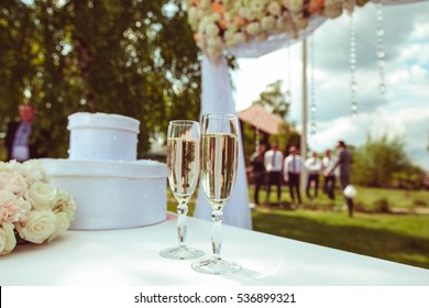 Two Glasses With Champagne Standing On The White Table