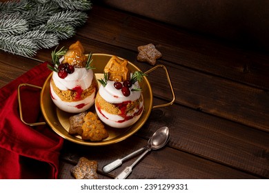 Two glasses of Christmas dessert with gingerbread cookies, whipped cream and cranberries on dark wooden background copyspace for text. High quality photo - Powered by Shutterstock