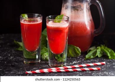 Two Glasses Of Freshly Made Strawberry Basil Lemonade With Swirly Straws On Dark Table