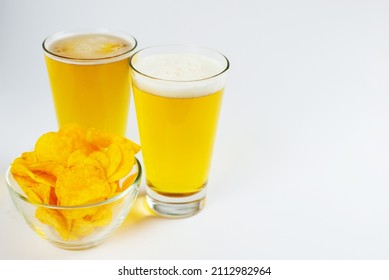 Two glasses of frothy beer, chips and beer bottles . Side view, space for copying.