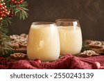 Two glasses of homemade eggnog with gingerbread cookies and Christmas decoration