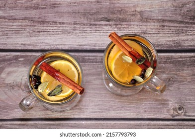 Two Glasses With Hot Herbal Tea With Cinnamon And Lemon Slices On A Wooden Table. Top View, Flat Lay.