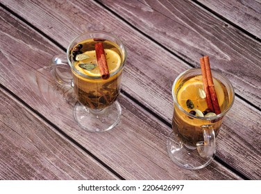 Two Glasses Of Hot Herbal Tea With Spices, Lemon And Cinnamon On A Wooden Table. Top View, Flat Lay.