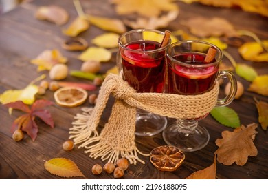 Two glasses of hot wine wrapped in one warm scarf on wooden table background, copy space. Autumn, autumn leaves. Seasonal drink, relaxing Sunday and the concept of care, love, warmth and comfort.
				
				