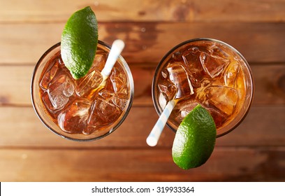 Two Glasses Of Iced Sweet Tea With Lime And Retro Paper Straws Shot Overhead On Wooden Table