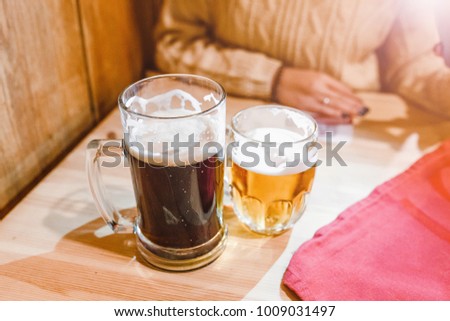 Two glasses of light and dark beer on an old wooden table in bar