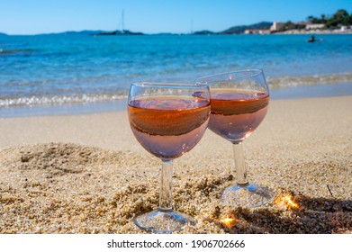 Two glasses of local rose wine on white sandy beach and blue Mediterranean sea on background, near Le Lavandou, Var, Provence, France