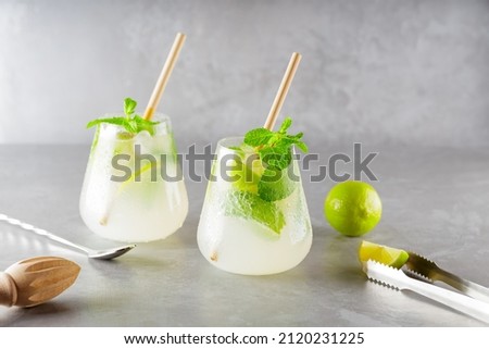Two glasses of mojito and bar accessories. Mojito cocktail on a gray background. Cocktail with lime and mint