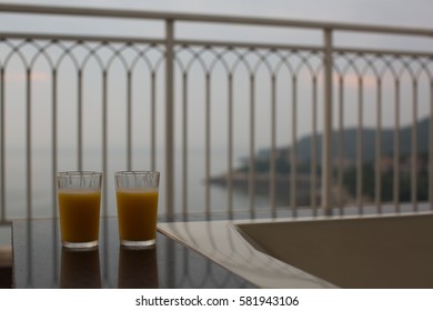 Two glasses of orange juice, beverage on a balcony overlooking nice coastal view in early morning or sunset