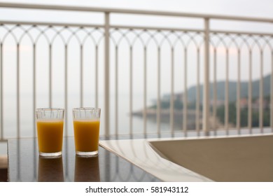 Two glasses of orange juice, beverage on a balcony overlooking nice coastal view in early morning or sunset