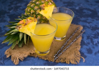 Two glasses of pineapple juice and fresh pineapple on a blue background. - Powered by Shutterstock