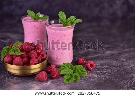Two glasses of raspberry smoothie on a black background. Copy space.
