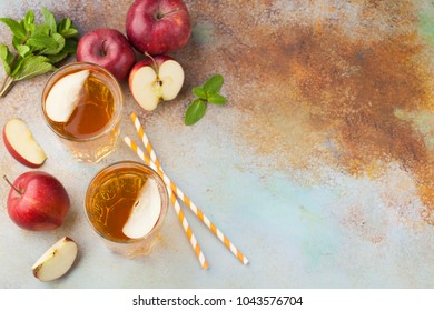 Two Glasses Of Red Apple Juice With Mint And Ice On An Old Rusty Table. Soft Drink On A Blue Background. Top View With Copy Space