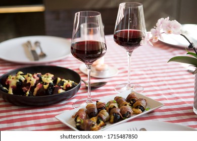 Two glasses of red Chianti wine on a dinner table, snacks on the background.