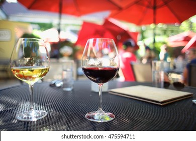 Two Glasses Of Red And White Wine Pair Of Red Pinot Noir And White Chardonnay On Beautiful Patio Dining Table Outdoors Under Umbrellas In The Summer