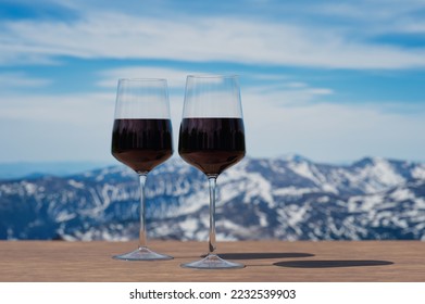 Two glasses of red wine against mountain background. View of snowy peaks in the mountains. - Shutterstock ID 2232539903