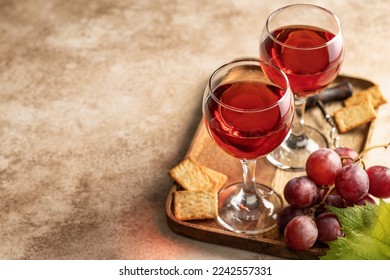 Two glasses of red wine, a bunch of red grapes, crackers and corkscrew on a wooden tray on beige textured background with text space. Party for two concept. Horisontal orientation - Powered by Shutterstock