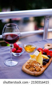 Two Glasses Of Red Wine And Cheese Plate On The Table At The Balcony. Fine Dining At Home.