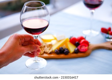 Two Glasses Of Red Wine And Cheese Plate On The Table At The Balcony. Fine Dining At Home.