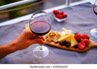 Two Glasses Of Red Wine And Cheese Plate On The Table At The Balcony. Fine Dining At Home.