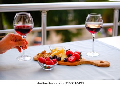 Two Glasses Of Red Wine And Cheese Plate On The Table At The Balcony. Fine Dining At Home.