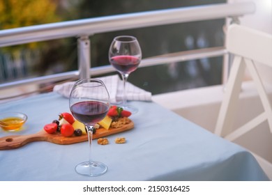 Two Glasses Of Red Wine And Cheese Plate On The Table At The Balcony. Fine Dining At Home.