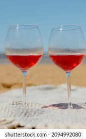 Two Glasses Of Red Wine Or Juice At A Picnic On The Shore Of A Lake Or Ocean. A Romantic Date Between Two People In Love. A Basket With Delicious Food For A Picnic And An Outdoor Dinner. Beautiful