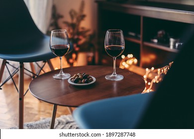 Two Glasses Of Red Wine And Olives On A Table, Cosy Room With Candid Lights, Concept Of Romantic Evening