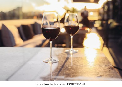 Two glasses of red wine on a rooftop terrace, sunset light 