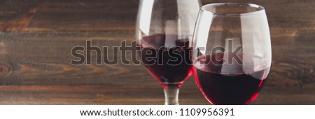 Two glasses of red wine on a brown wooden table. Alcoholic beverages. banner. Red wine. Winer. Glass with wine.