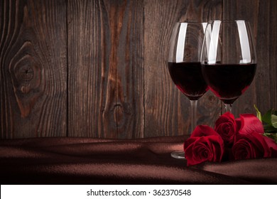 Two Glasses Of Red Wine And Red Roses On Brown Silk