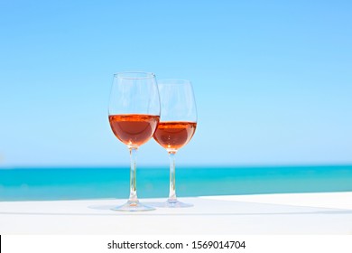 Two Glasses Of Rose Wine Against Blue Water And Sea In Summer Day