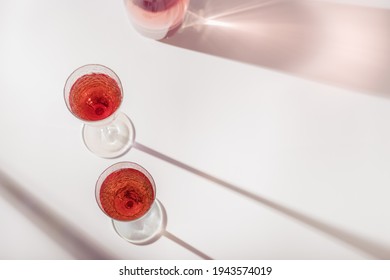 Two Glasses Of Rose Wine Or Champagne Sweet And Dry, Top View And Shadows From Sun. Light Alcohol Sparkling Drink For Party. Flat Lay On Light Table At Summer Day. 