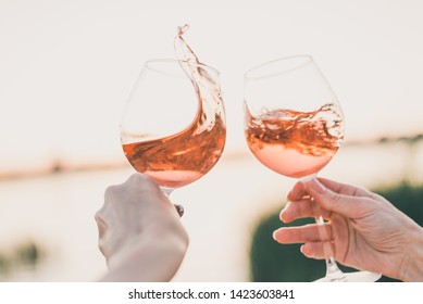 Two glasses of rose wine in hands against the sunset sky. - Powered by Shutterstock