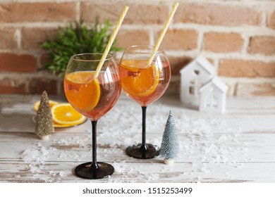 Two Glasses Of Rossini Prosecco Cocktail With Orange Slices On Wooden Background With Christmas Decoration. Christmas Party Beverage.